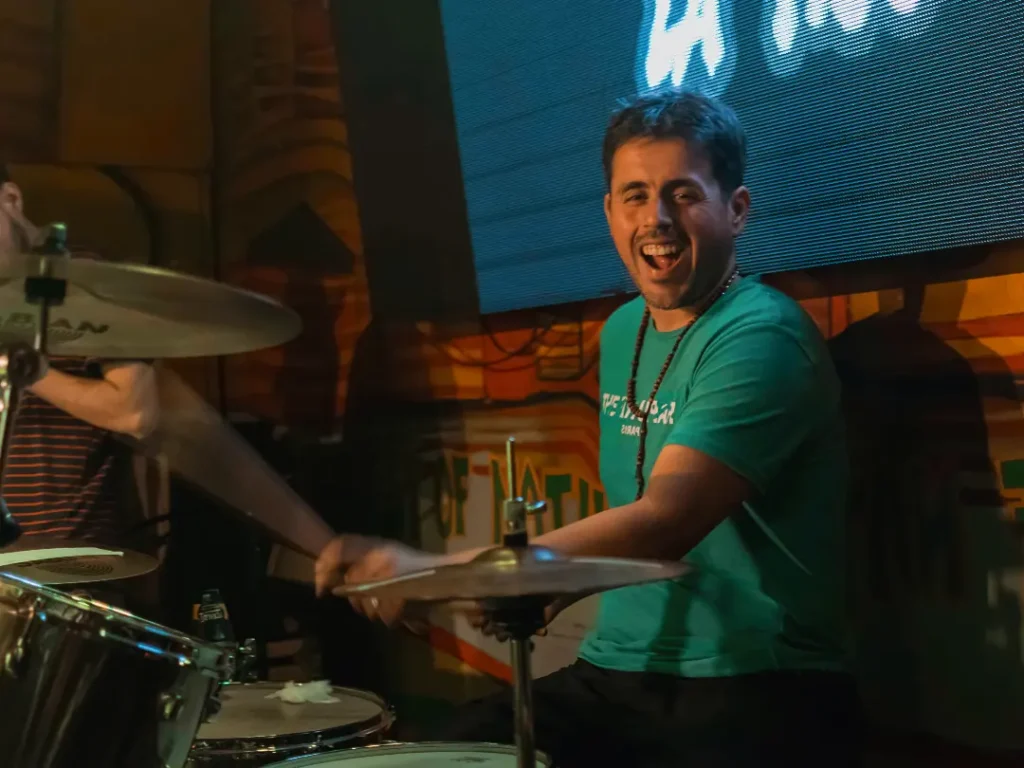 Integrante de La Tico tocando la batería y cantando en vivo, banda formada en Collegium